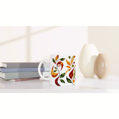 Product mockup: white mug with a colorful orange-green leaf pattern, placed beside books and vases on a light desk.