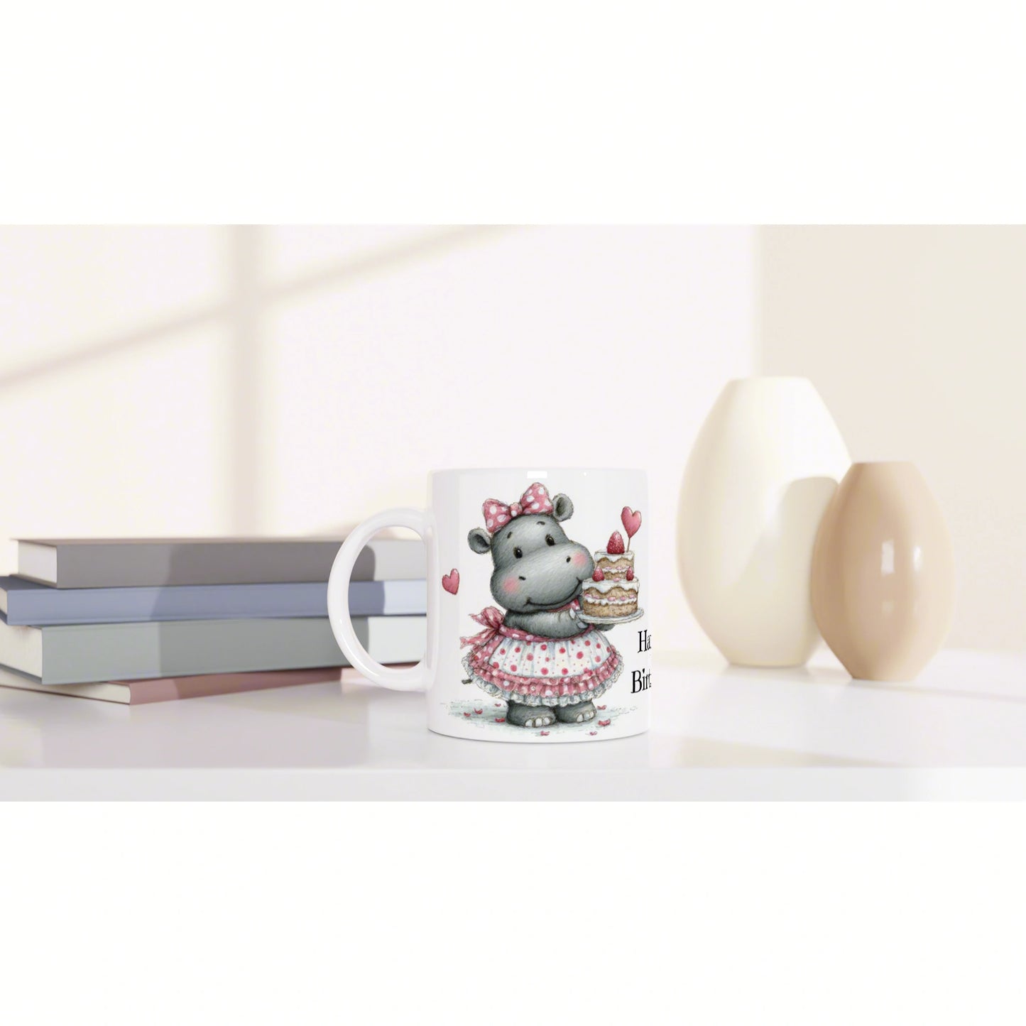 White mug featuring a cute hippo in a pink dress holding a cake, on a desk with books and vases - product mockup.