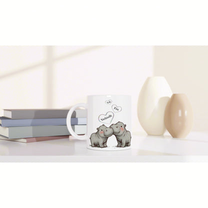 Product mockup: white mug with two elephants kissing and heart-shaped captions, beside stacked books and cream/beige vases.
