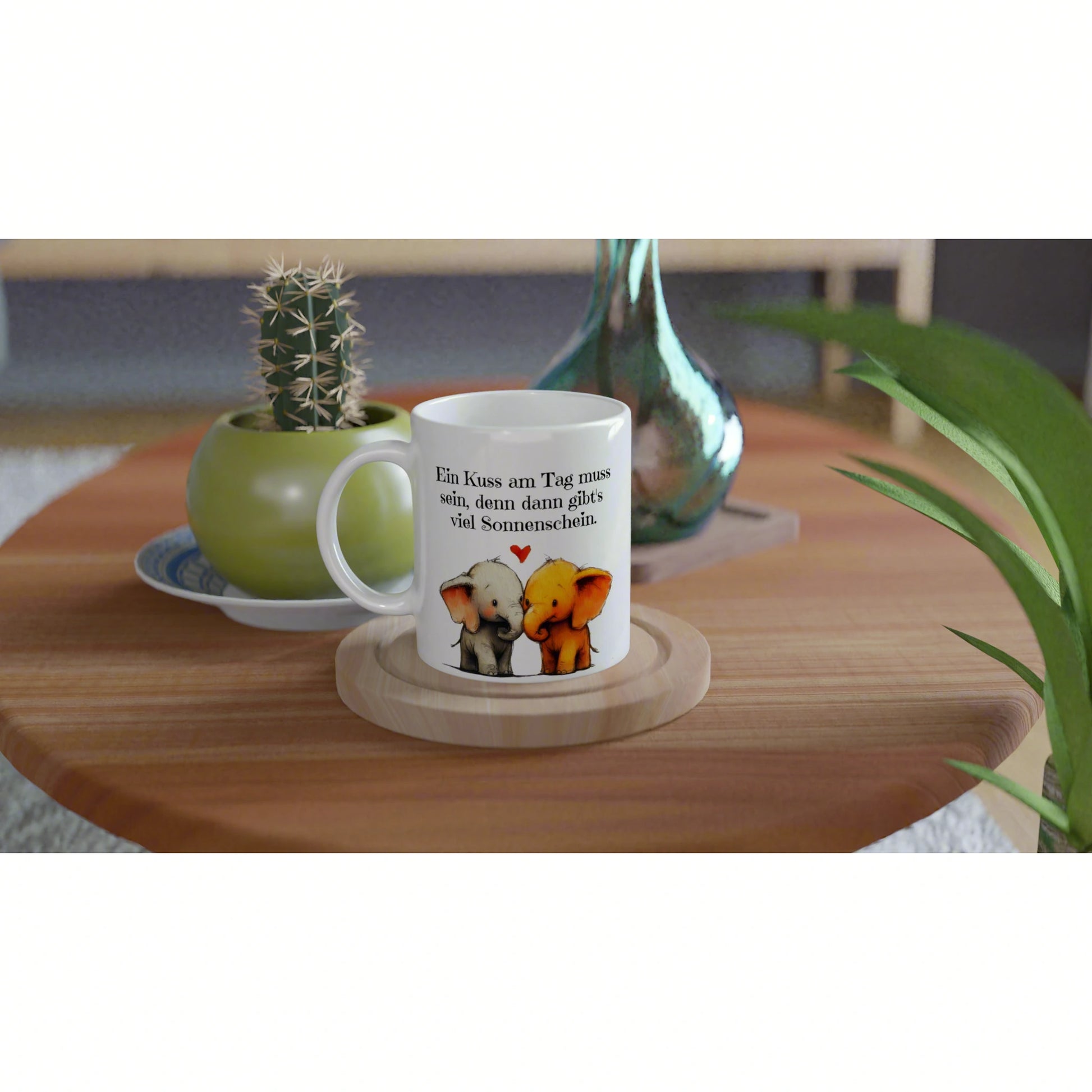 White mug featuring two elephants kissing with a German caption about sunshine on a wooden coaster near potted plants.