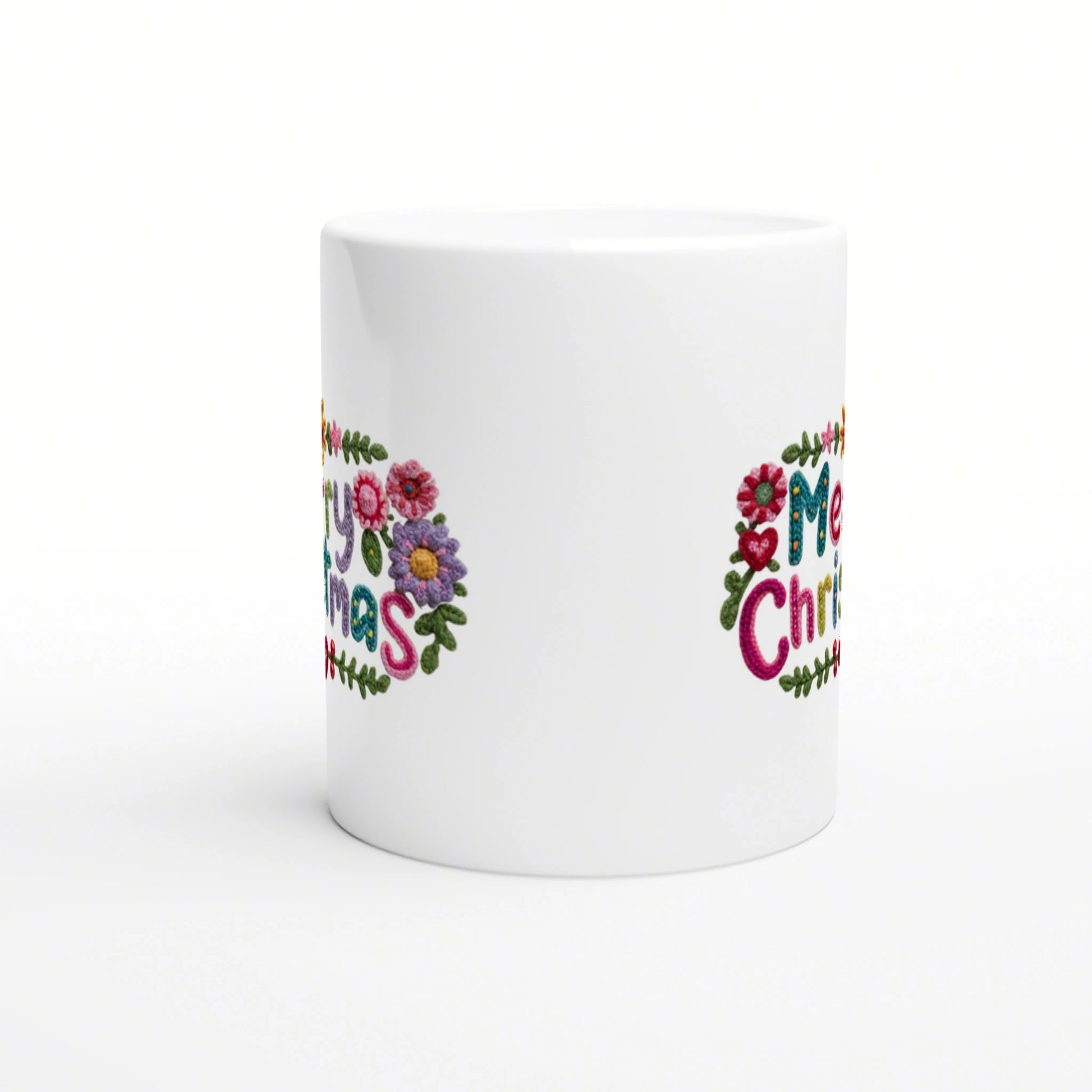 White ceramic mug with colorful floral embroidery spelling Merry Christmas around the side.
