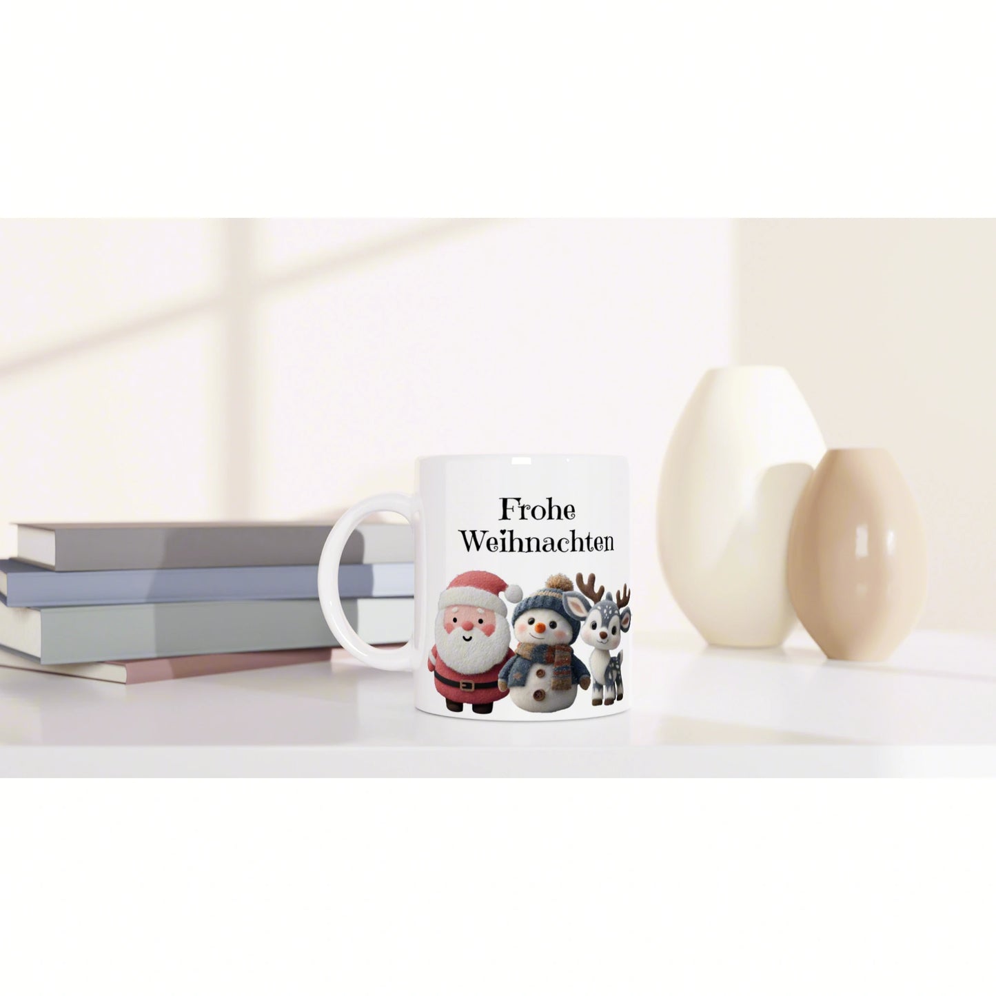 White mug with Frohe Weihnachten and cute Santa, snowman, and reindeer, on a desk with books and decorative vases.