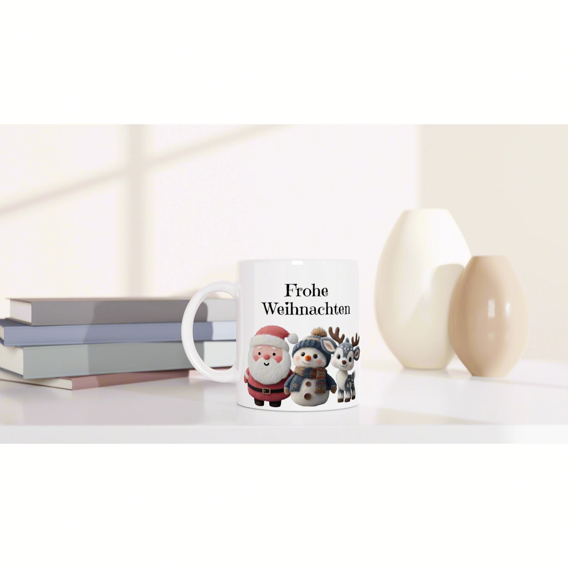 White mug with Frohe Weihnachten and cute Santa, snowman, and reindeer, on a desk with books and decorative vases.