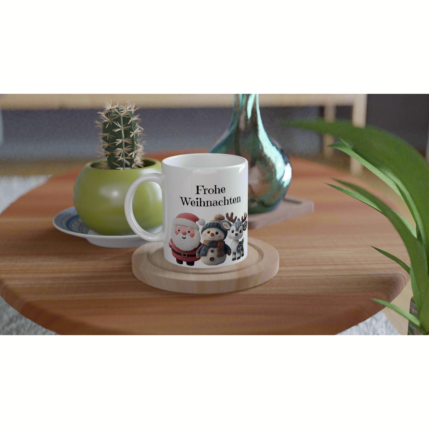White mug with Frohe Weihnachten and cute Santa, snowman, and reindeer, on a wooden table with plants in the background.