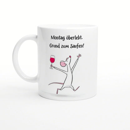 White mug featuring the German slogan 'Montag überlebt. Grund zum Saufen!' with a cheerful cartoon mouse raising a wine glass.