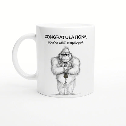 White mug featuring a hand-drawn gorilla in a suit with a medal and the caption Congratulations, you're still employed