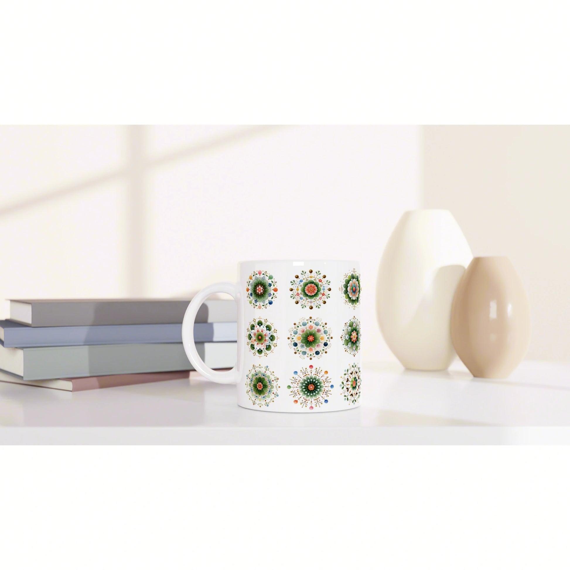 White mug with a repeating green floral medallion pattern, shown as a product mockup beside books and decorative vases.