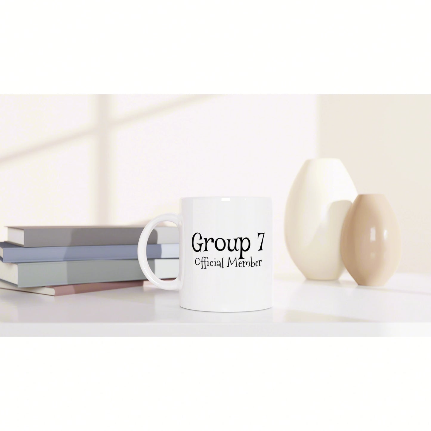 White mug with 'Group 7 Official Member' text on a shelf beside stacked books and decorative vases.