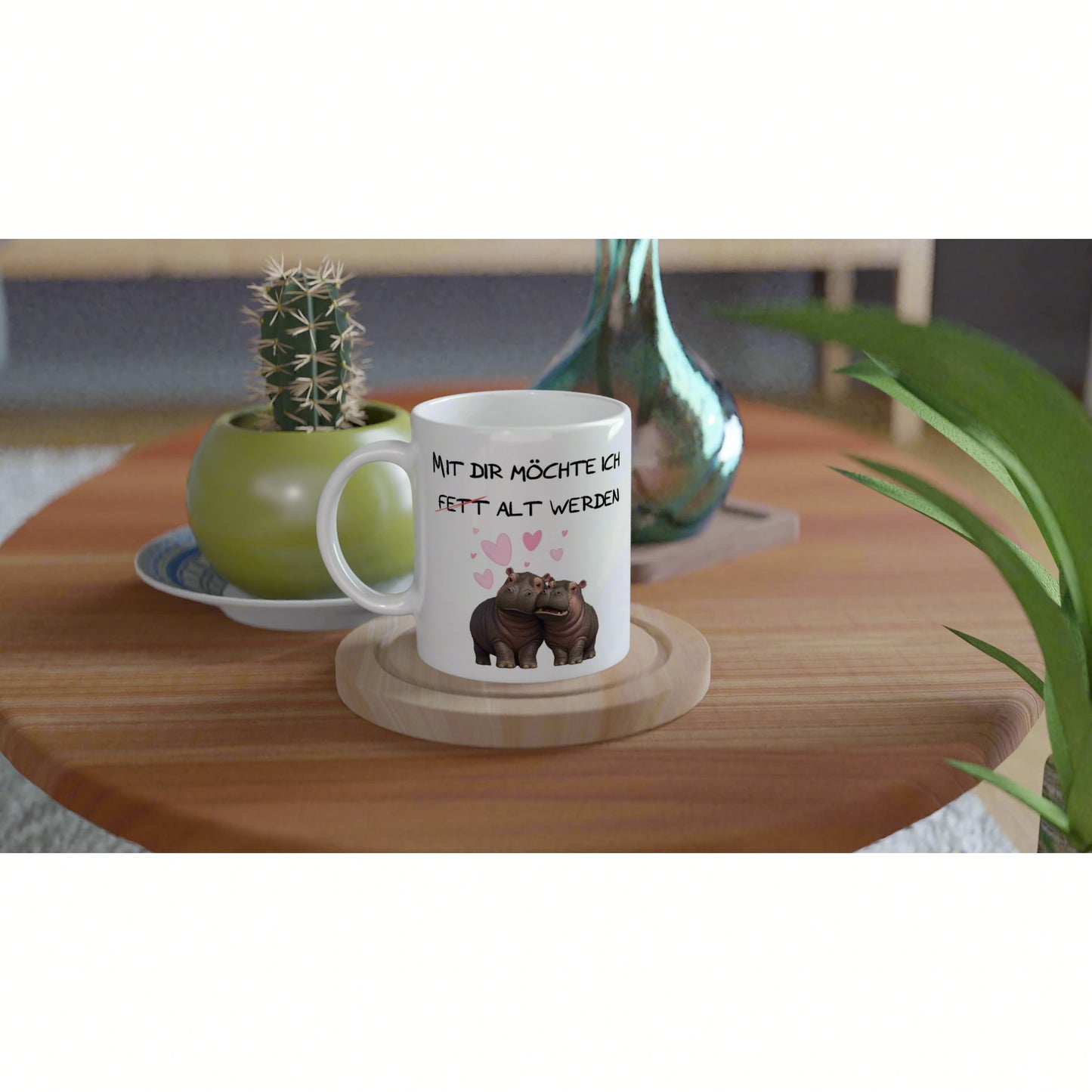 White mug mockup with cartoon hippos and pink hearts, German slogan, on a wooden table with plants.
