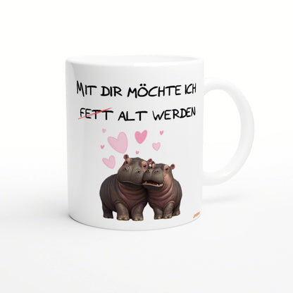 White mug mockup with two hippos, pink hearts, and the German text 'Mit dir moechte ich fett alt werden'.
