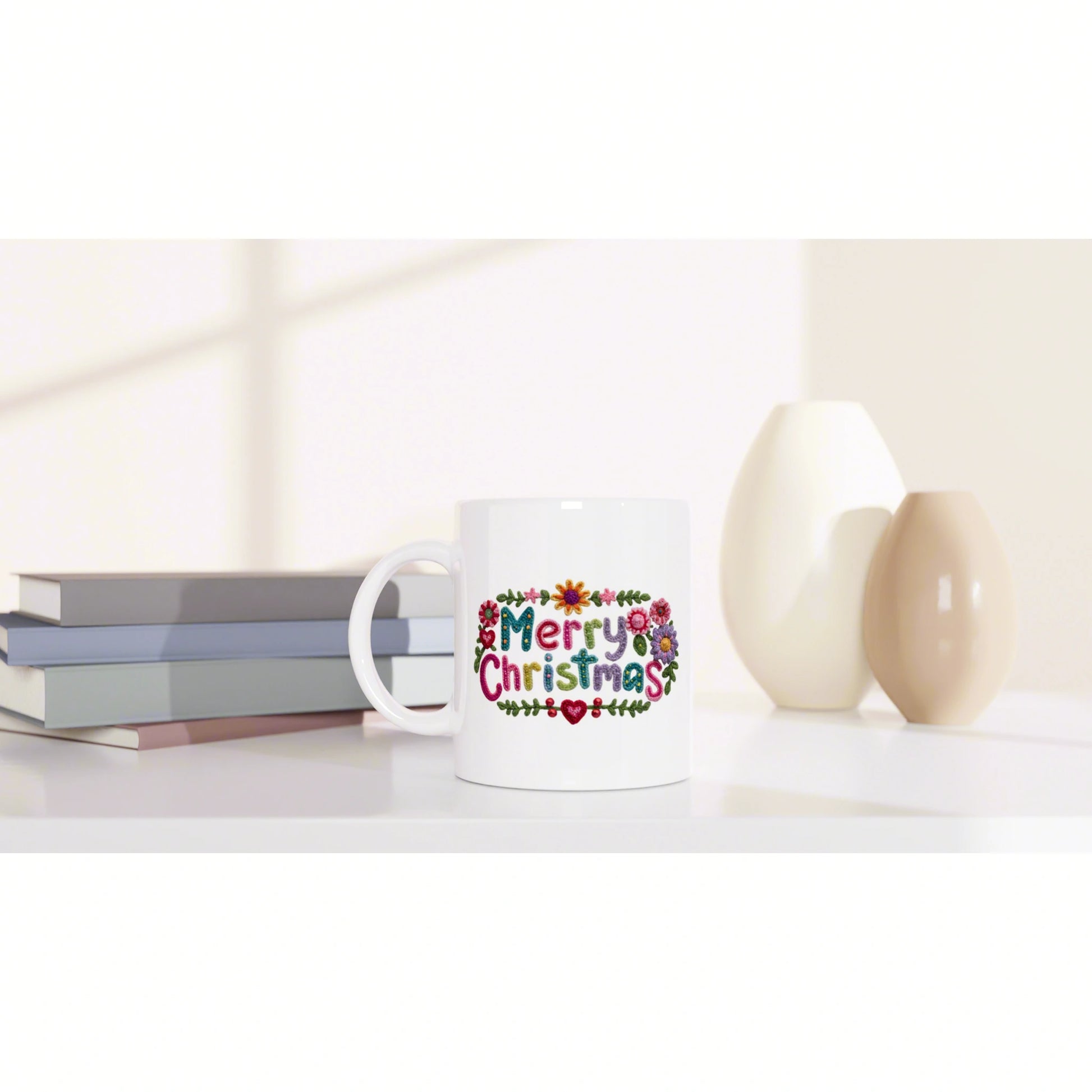White mug with a colorful embroidered 'Merry Christmas' design, shown as a product mockup on a desk