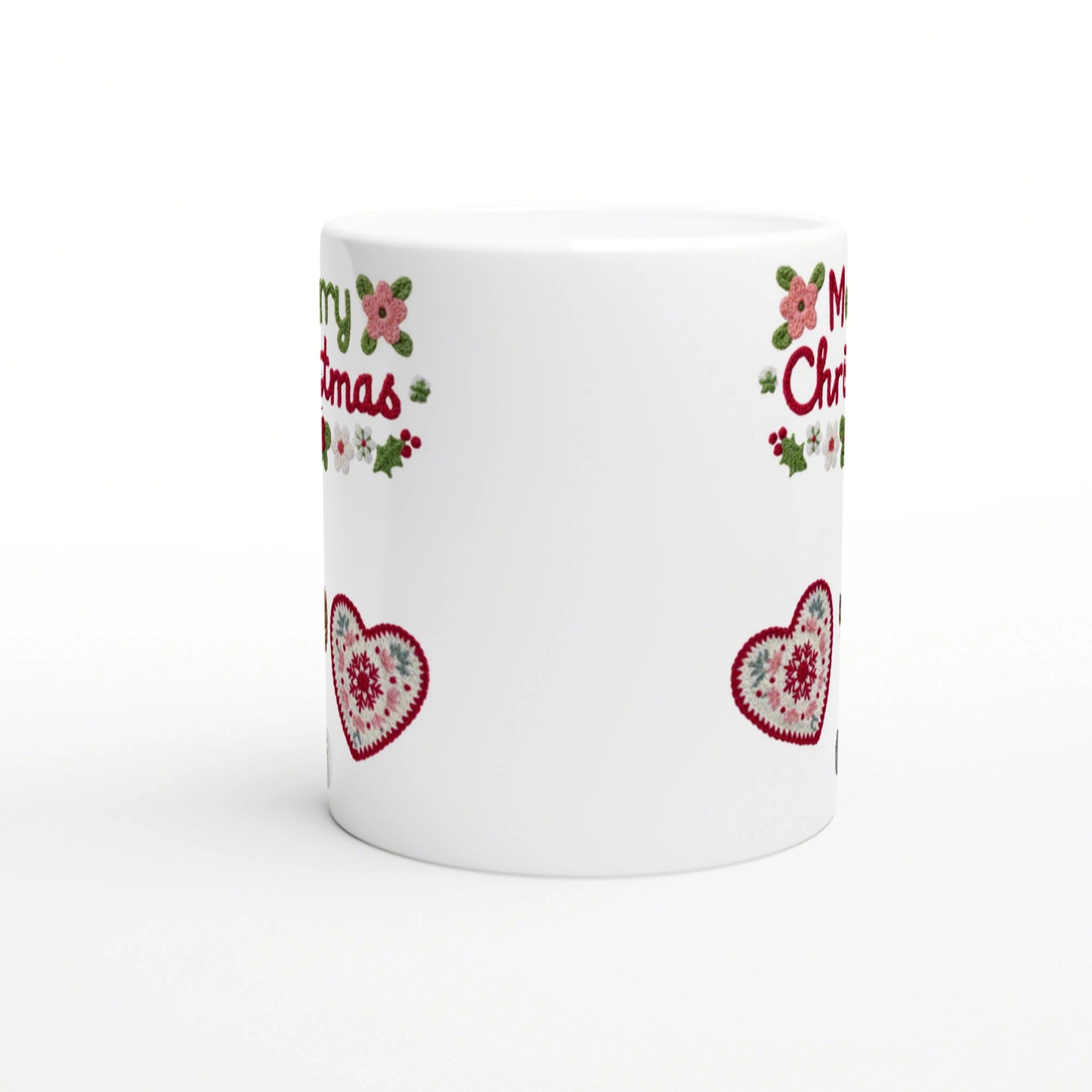 White mug mockup with Christmas border: red crocheted hearts, holly, pink flowers, and partial red lettering near the rim.