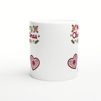 White mug mockup with Christmas border: red crocheted hearts, holly, pink flowers, and partial red lettering near the rim.