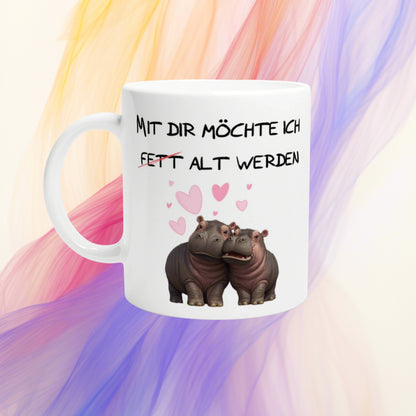 White mug mockup with German slogan Mit dir moechte ich fett alt werden, featuring two hippos and pink hearts.
