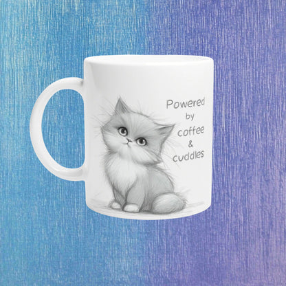 White mug mockup with a pencil sketch kitten and the caption Powered by coffee & cuddles on a blue textured background.