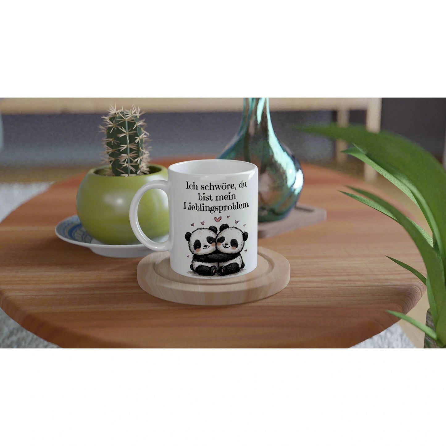 White mug with a panda couple illustration and the caption 'Ich schwöre, du bist mein Lieblingsproblem' on a wooden coaster.