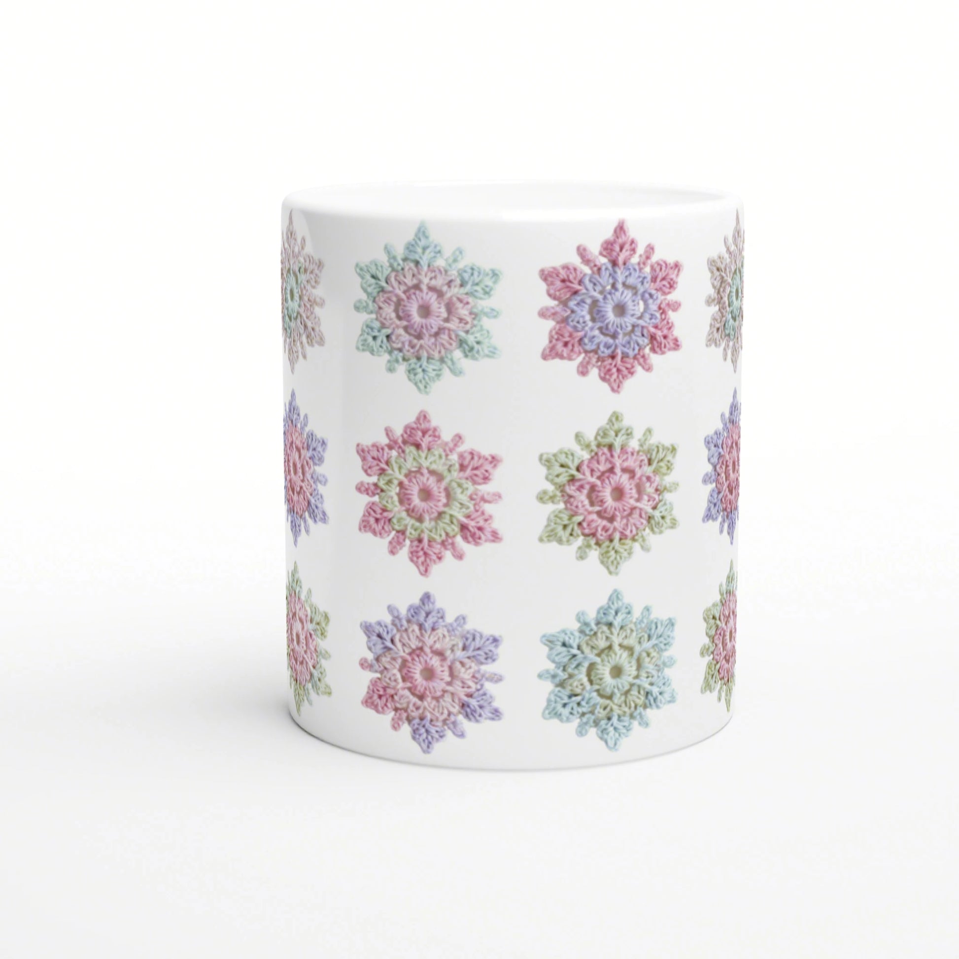 White mug with pastel crochet flower pattern wraparound in pink, blue, green and lavender.