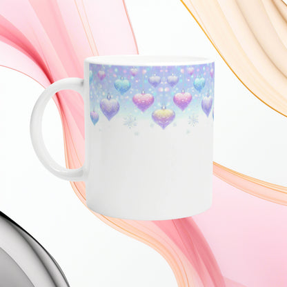 White mug with pastel blue gradient band, hanging heart ornaments and snowflakes; pink and peach flowing ribbons backdrop.