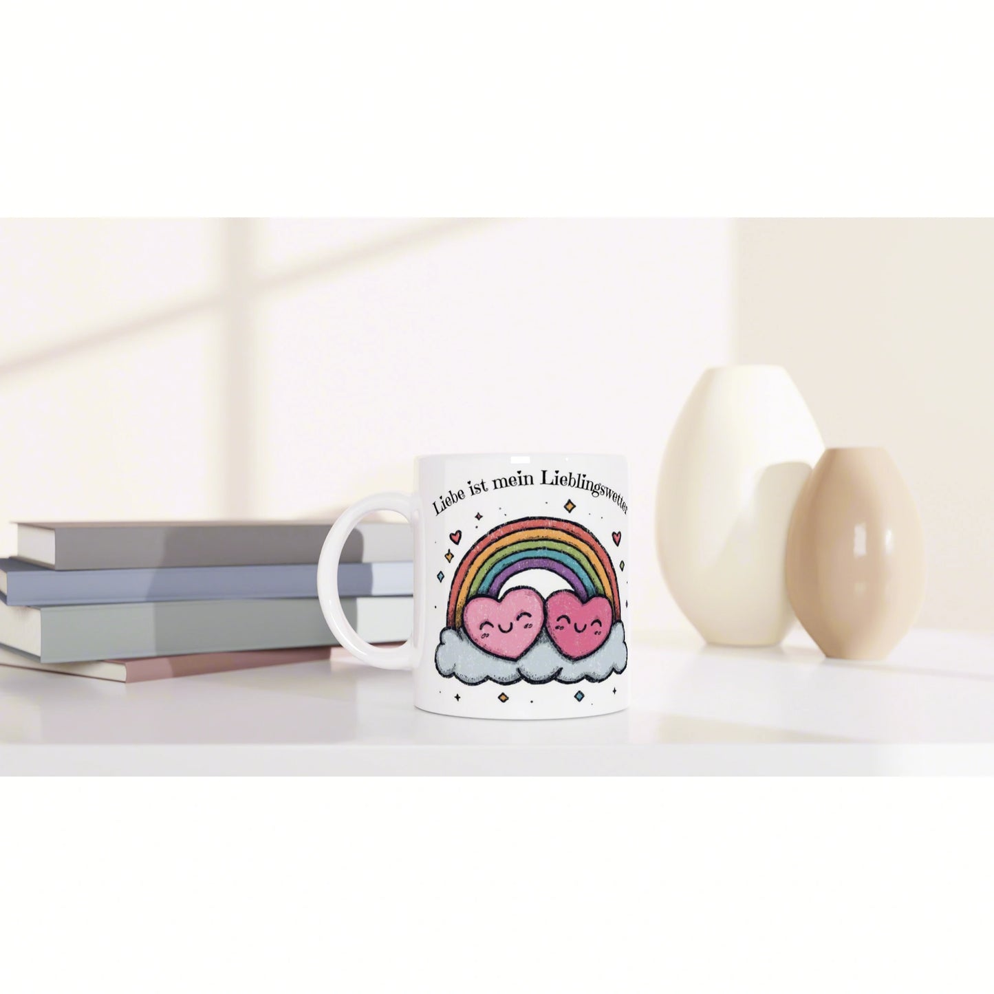 White mug featuring rainbow, hearts, and clouds with German text; sits on a desk beside books and ceramic vases.
