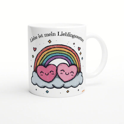 White mug featuring a rainbow arch, two smiling pink hearts on clouds, and the German caption Liebe ist mein Lieblingswetter.