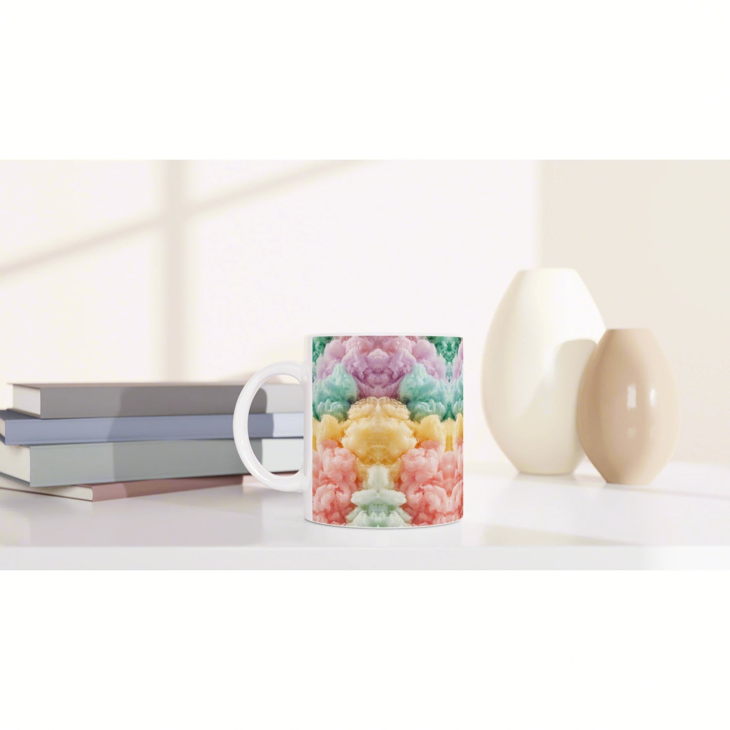 Product shot of a white mug with a vibrant cloud-like rainbow pattern, set beside books and minimalist vases on a shelf.