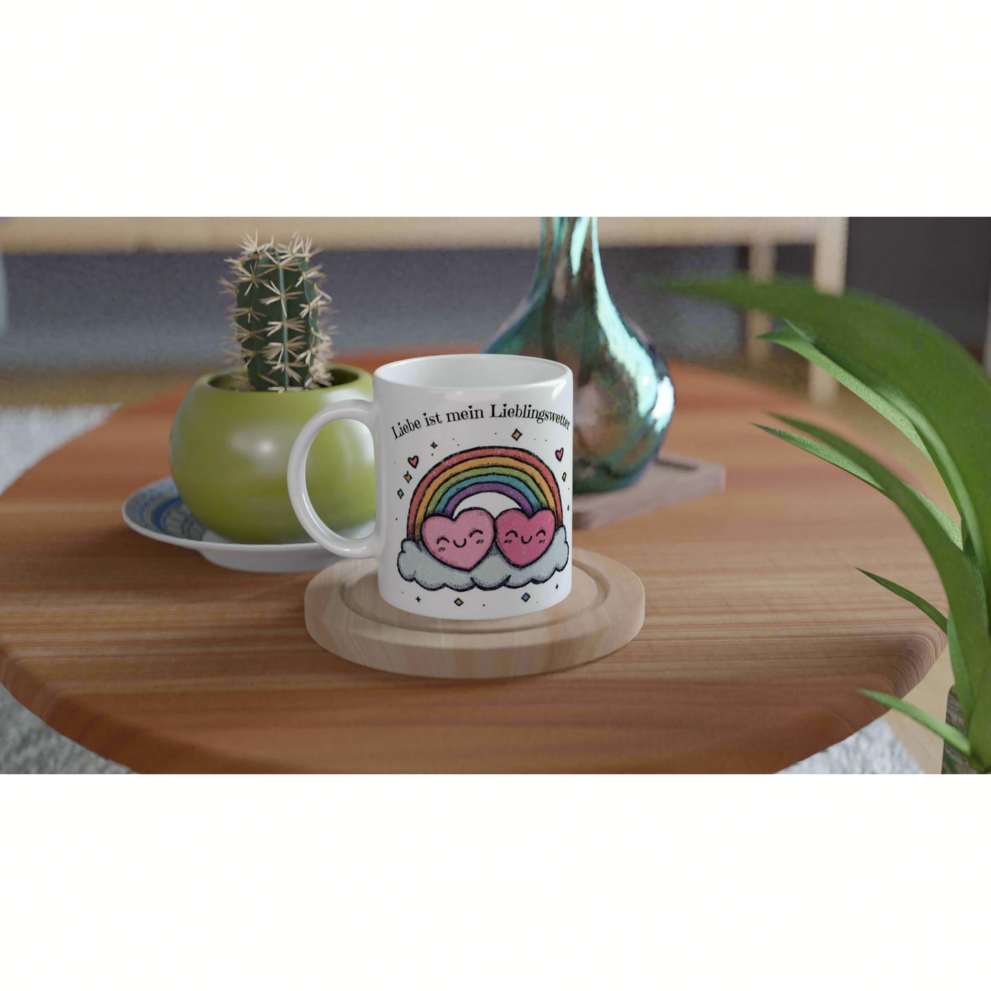 White mug with a rainbow and smiling pink heart clouds; text 'Liebe ist mein Lieblingswort' on a wooden table.