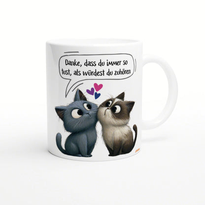 White mug featuring two cartoon cats looking at each other; speech bubble in German about pretending to listen.
