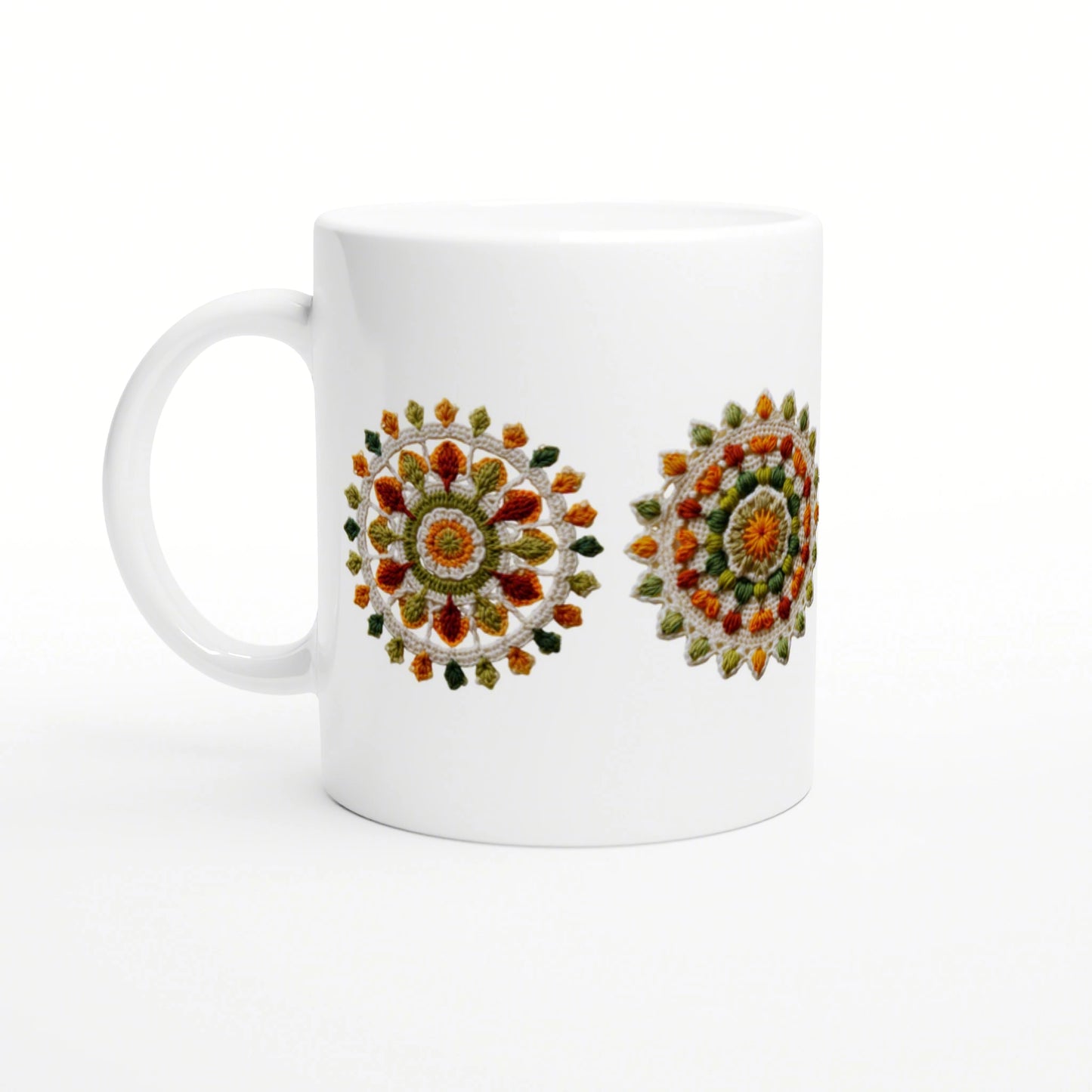 White ceramic mug displaying two colorful circular mandala embroidery motifs on its side.