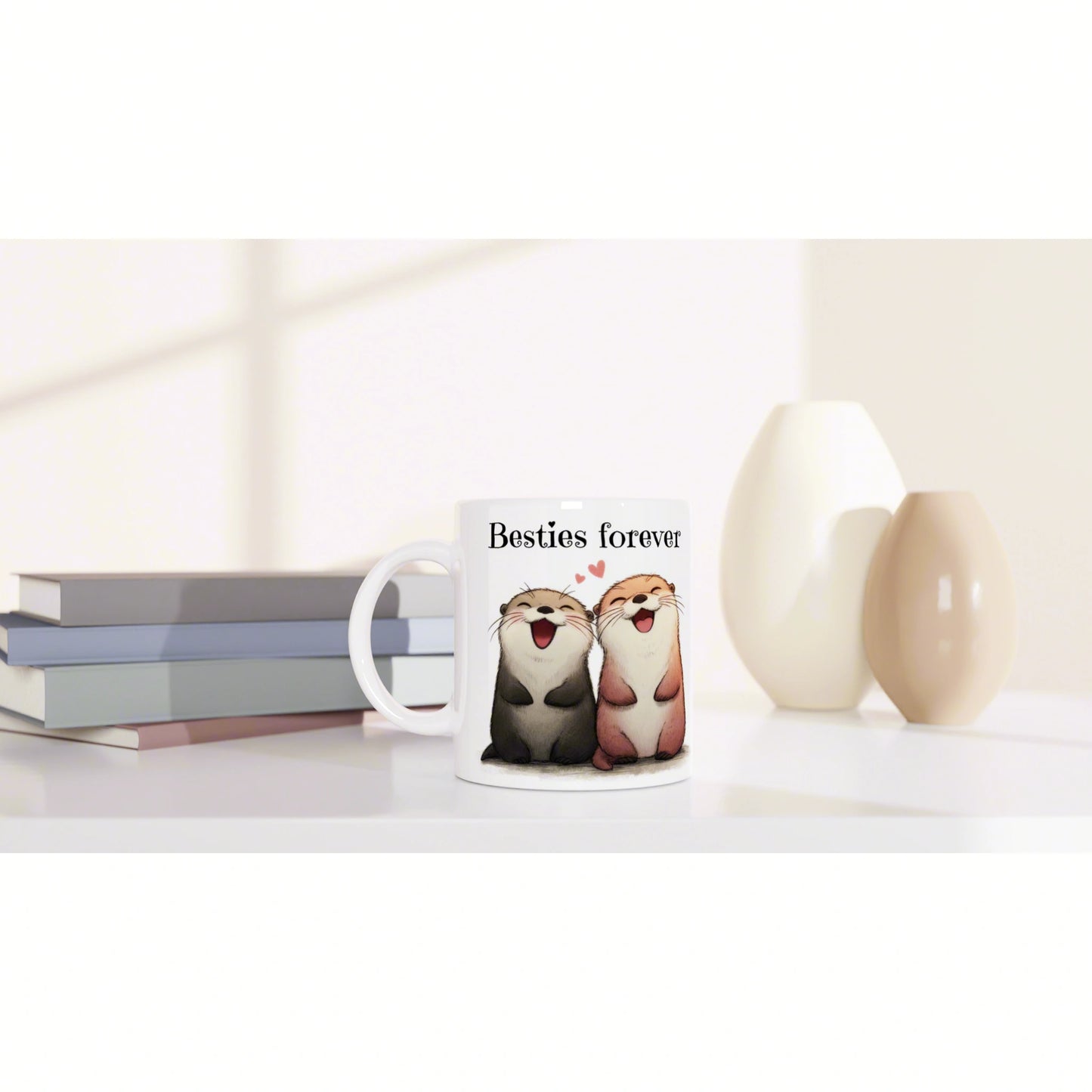 White mug with two smiling otters and Besties forever text, shown with books and decorative vases on a shelf.