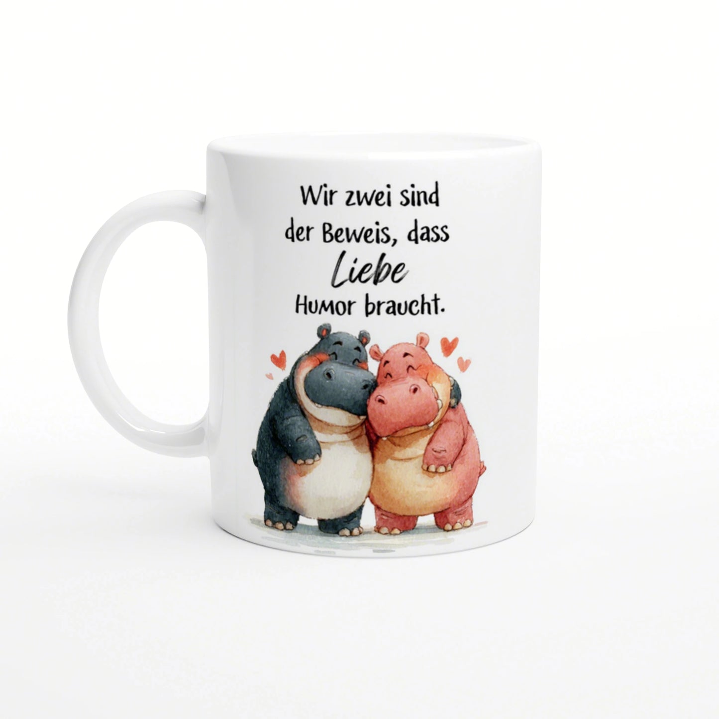 White mug with a watercolor illustration of two hugging hippos, hearts, and a German slogan about love needing humor.