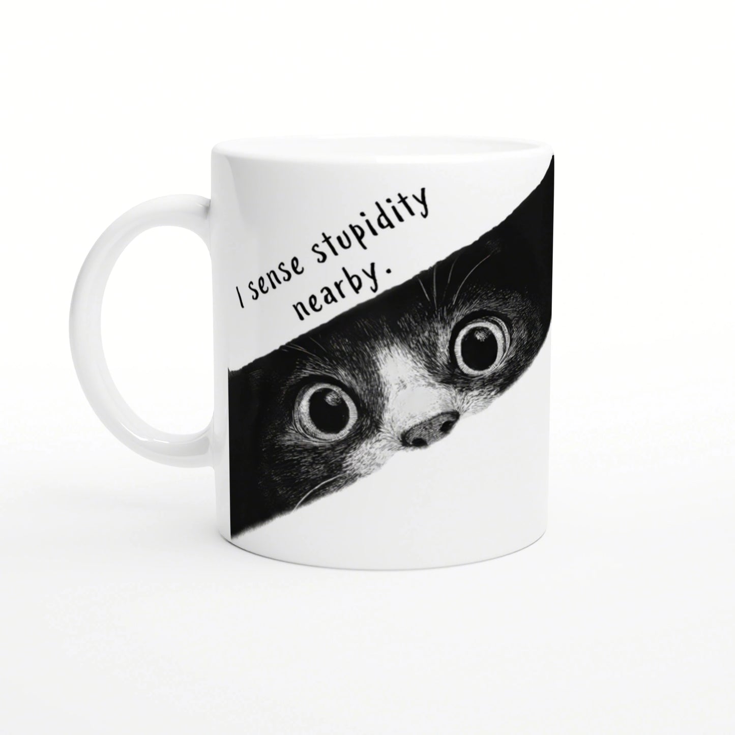 White mug with a black-and-white illustration of a wide-eyed animal peeking from a torn banner that reads I sense stupidity nearby