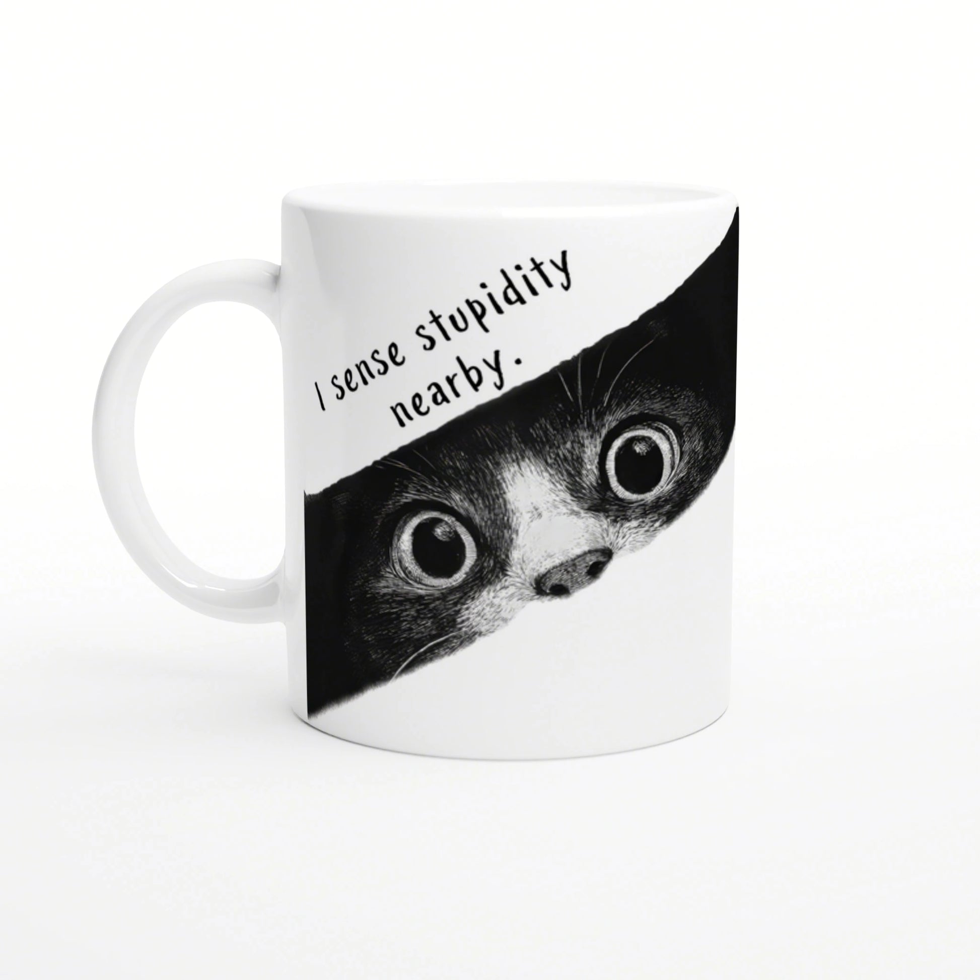White mug with a black-and-white illustration of a wide-eyed animal peeking from a torn banner that reads I sense stupidity nearby
